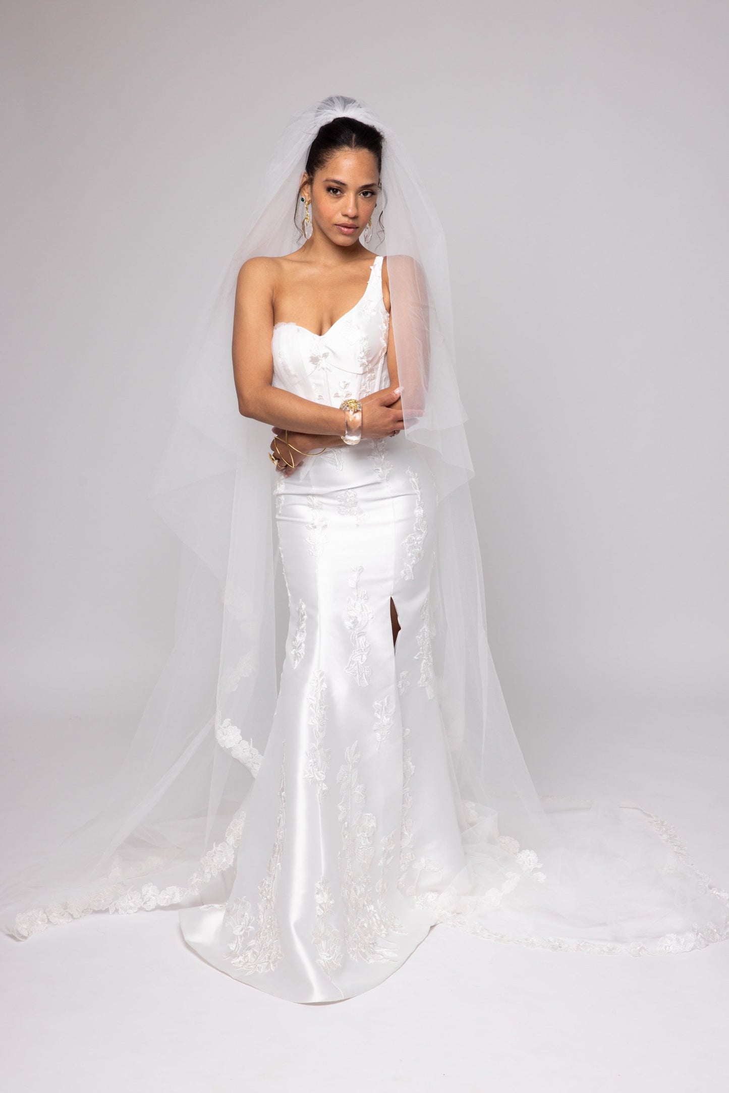 Off-white Mikado gown with embroidered lace, one shoulder with tulle detail over left bust. Detachable peplum.