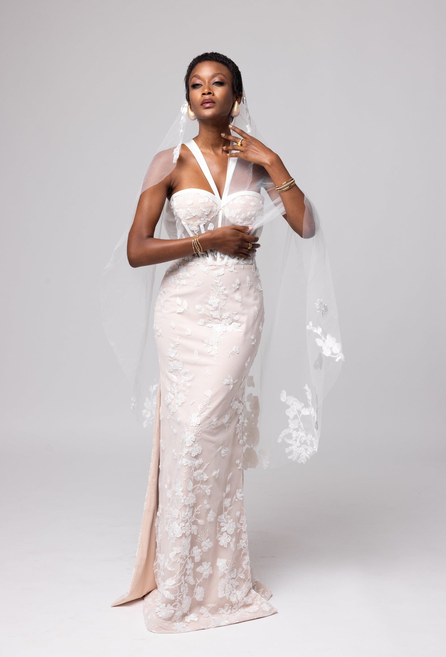 Nude underlay lace gown, white piping details, halter neckline with side slits. Large cascading bow in the back.