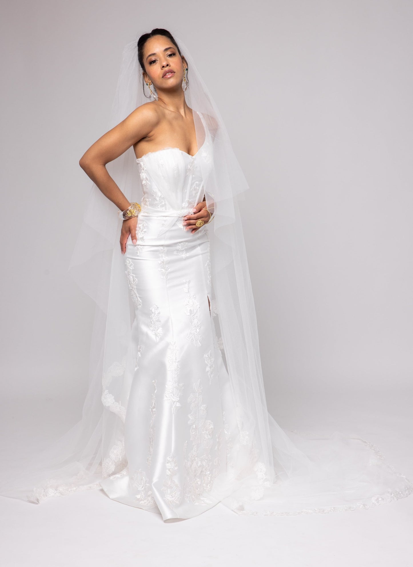 Off-white Mikado gown with embroidered lace, one shoulder with tulle detail over left bust. Detachable peplum.