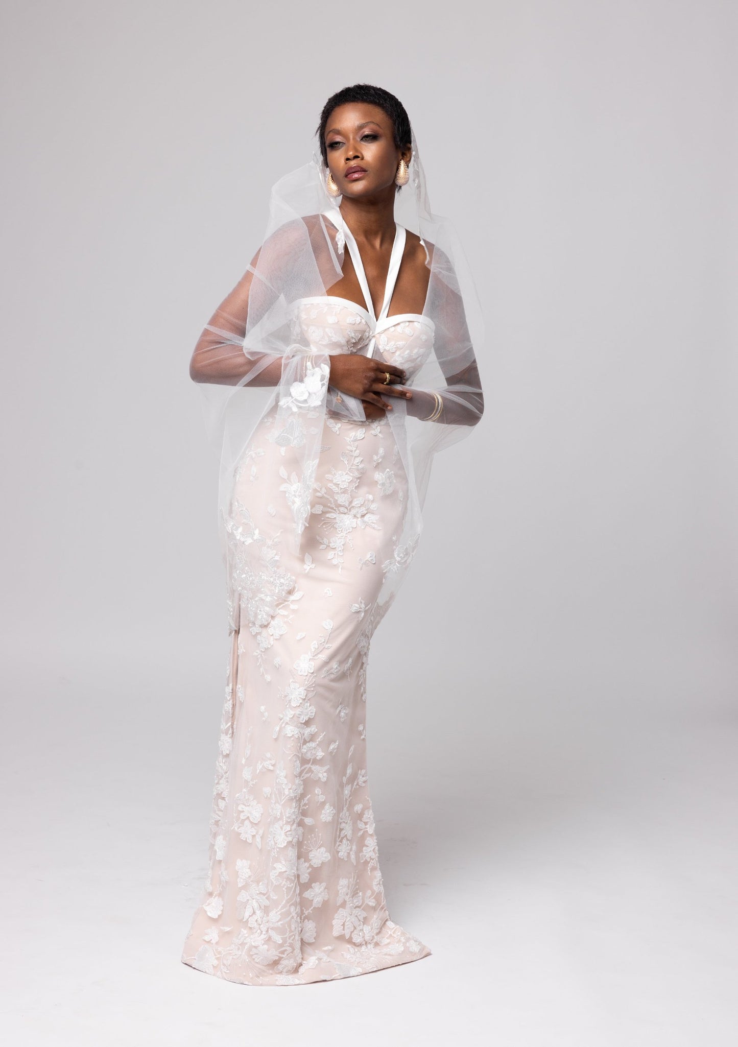 Nude underlay lace gown, white piping details, halter neckline with side slits. Large cascading bow in the back.