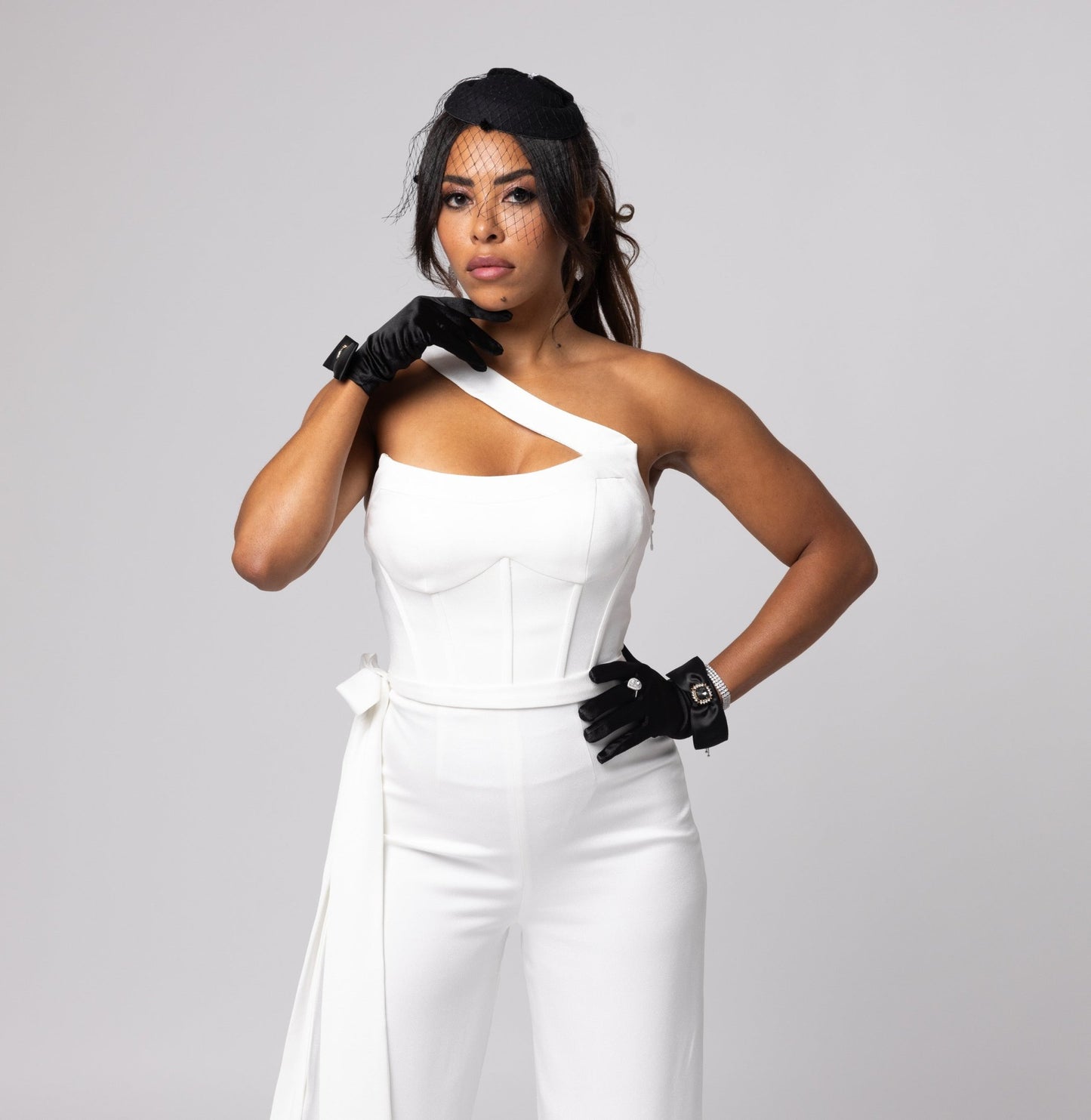 Off-white scoop neckline one shoulder jumpsuit. Long, side bow at waist, cuffed hemline.