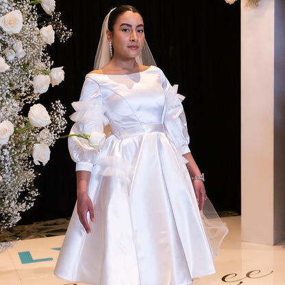 Knee length, boat neck dress of satin and tulle detailing.&nbsp; Three quarter sleeves, it is perfect as a day wedding or a fancy bridal shower dress.