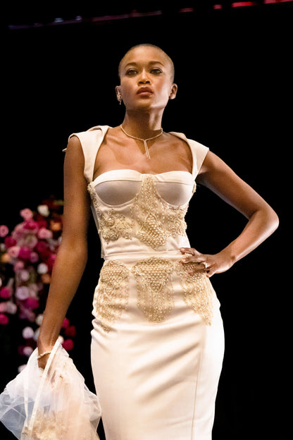 Beaded, embroidered gown is boldly cut; sheer laced corset back is very open with a collar. Below the waist is fitted, flowy with a thigh-high slit.