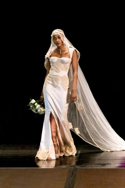 Beaded, embroidered gown is boldly cut;&nbsp; sheer laced corset back is very open with a collar. Below the waist is fitted, flowy with a thigh-high slit.