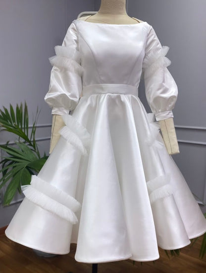 Knee length, boat neck dress of satin and tulle detailing.&nbsp; Three quarter sleeves, it is perfect as a day wedding or a fancy bridal shower dress.